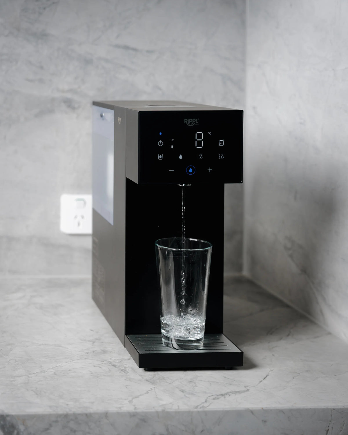 Rippl Nano in Black pouring a glass of water on a marble bench