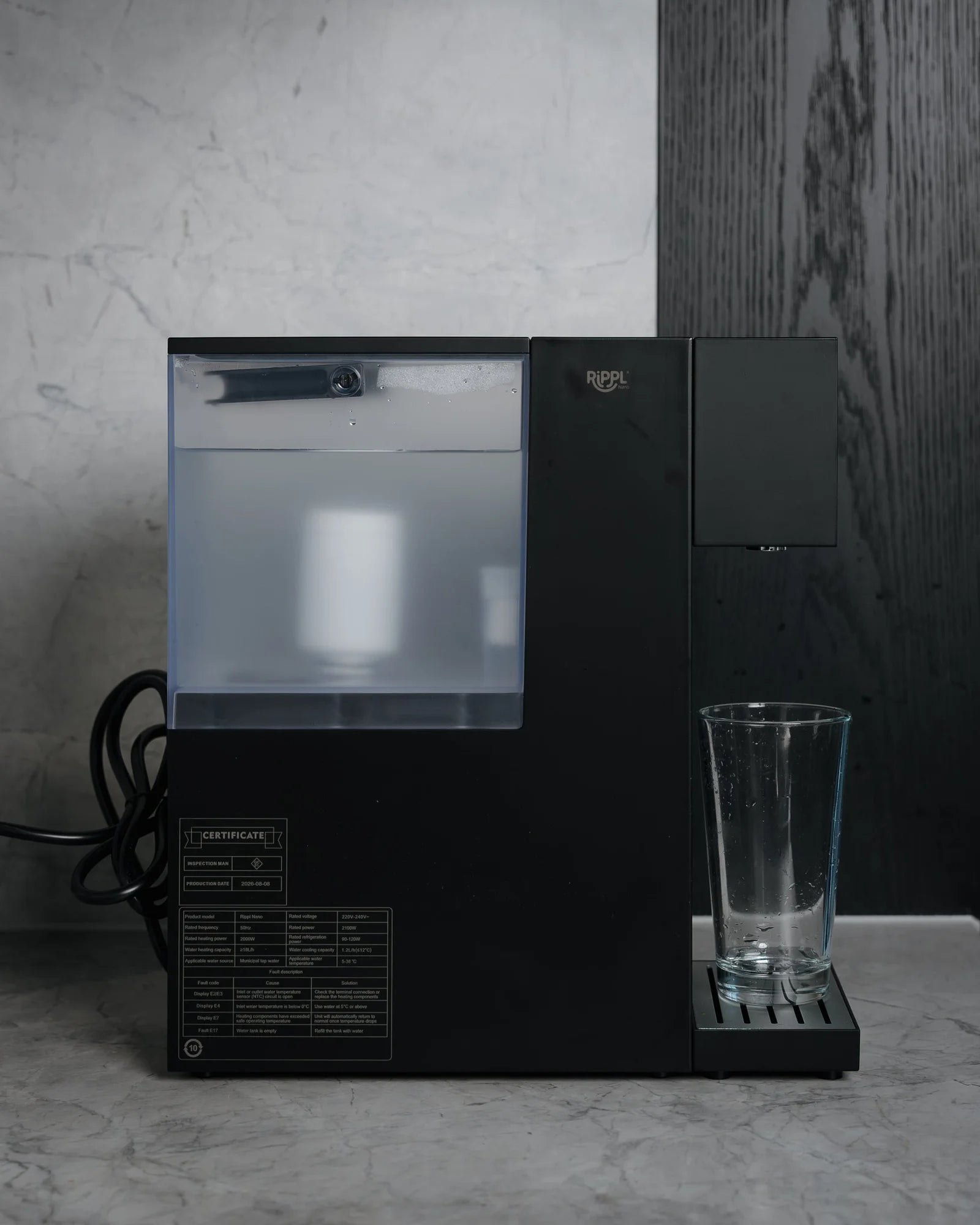 Rippl Nano in Black, side on, on a kitchen bench beside a glass